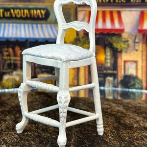 May include: White wooden chair with a carved back and a silver glitter seat. The chair has a simple design with a single rung and four legs.