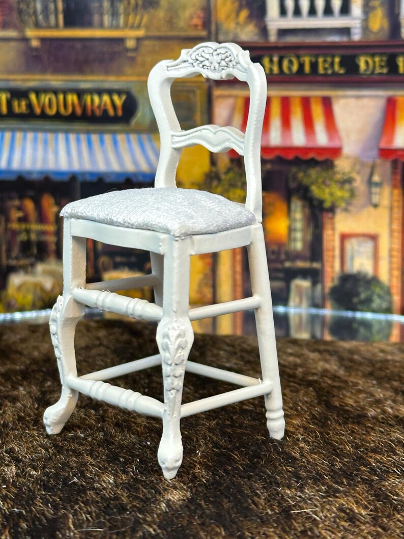May include: White wooden chair with a carved back and a silver glitter seat. The chair has a simple design with a single rung and four legs.