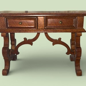 Peut inclure: Petite table en bois brun foncé avec deux tiroirs et des pieds ornés. Les tiroirs ont des boutons en laiton. Les pieds présentent un motif incurvé et décoratif.