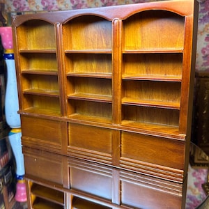 Könnte beinhalten: Ein Bücherregal aus Holz mit gewölbten Oberteilen und mehreren Regalbrettern. Das Bücherregal ist aus dunkelbraunem Holz gefertigt und hat eine Antik-Optik.