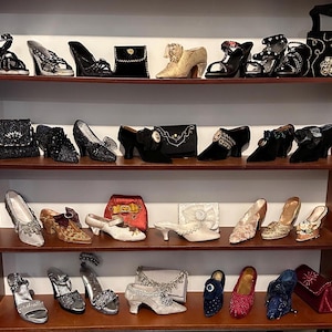 Puede incluir: Un estante con una colección de zapatos y bolsos en miniatura. Los zapatos son de varios colores y estilos, incluyendo negro, blanco, dorado y rojo. Los bolsos también son de varios colores y estilos, incluyendo negro, rojo y dorado.