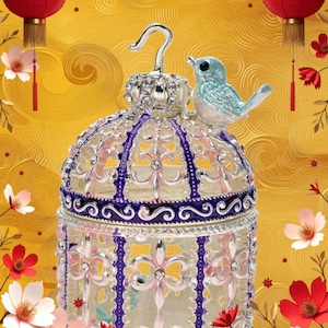 May include: A decorative birdcage-shaped trinket box with a blue bird perched on top. The cage is clear with silver and purple accents, and is decorated with floral designs. Red lanterns and flowers adorn the gold background.