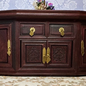 May include: A dark wood jewelry box with intricate carvings and brass hardware. The box has two doors with brass handles and two drawers with brass knobs.