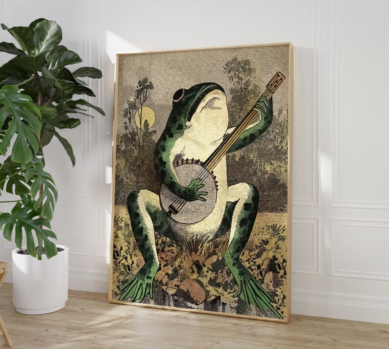 May include: A green frog playing a banjo with a brown wooden body and white strings. The frog is sitting on a brown and green background with leaves and flowers.
