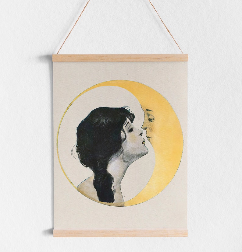 May include: A vintage-style print featuring a woman and a crescent moon in a romantic embrace. The artwork is in soft tones, with the woman's dark hair contrasting against the pale background. The print is held by wooden bars and a hanging string.