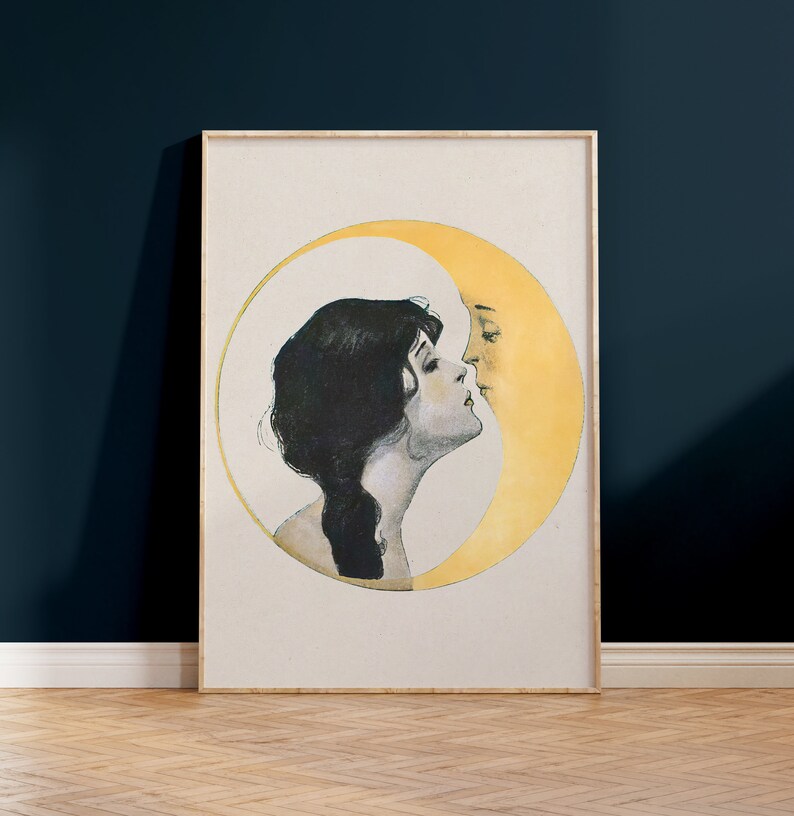May include: Framed vintage art print featuring a woman and a crescent moon in a romantic embrace. The artwork is in a soft color palette with a cream background, a yellow moon, and a woman with dark hair. The frame is a light wood color.