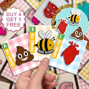 May include: Four enamel pins featuring a bee with the text "Bee Kind", a poop emoji, a human heart with anatomical labels, and a poop emoji with a smiley face. The pins are displayed on a checkered background with the text "Buy 4 Get 1 Free" and "Stickers Available!" in the background.