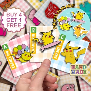 Może przedstawiać: Trzy szpilki emaliowane z postacią kreskówkowego Pikachu w różnych pozach. Szpilki znajdują się na kartkach z różowym, niebieskim i jasnoniebieskim tłem w kratkę. Kartki mają napis "Enamel Pin" i litery A, B i C. Napis "Stickers Available!" znajduje się na niebieskim tle z białymi literami. Napis "Hand Made" znajduje się na różowym tle z białymi literami.