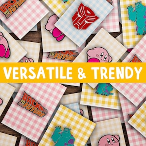May include: A collection of colorful enamel pins featuring various pop culture characters and logos, including a pink Kirby character, a blue monster, a red Transformers logo, and a Back to the Future logo. The pins are displayed on a checkered background with the text "VERSATILE & TRENDY" in yellow.