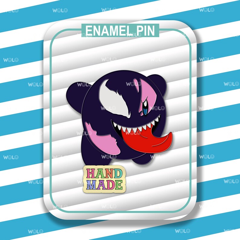 K&ouml;nnte beinhalten: Eine schwarze, rosa und rote Emaille-Anstecknadel mit einer Cartoon-Figur mit einem gro&szlig;en, zahnigen Grinsen. Die Anstecknadel ist mit "HAND MADE" beschriftet.