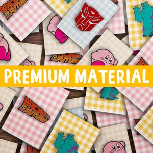 May include: A collection of colorful enamel pins featuring various pop culture characters and logos, including 'Back to the Future', 'Transformers', 'Kirby', and 'Monsters Inc'. The pins are displayed on a pink and yellow checkered background with the text 'PREMIUM MATERIAL' in yellow.