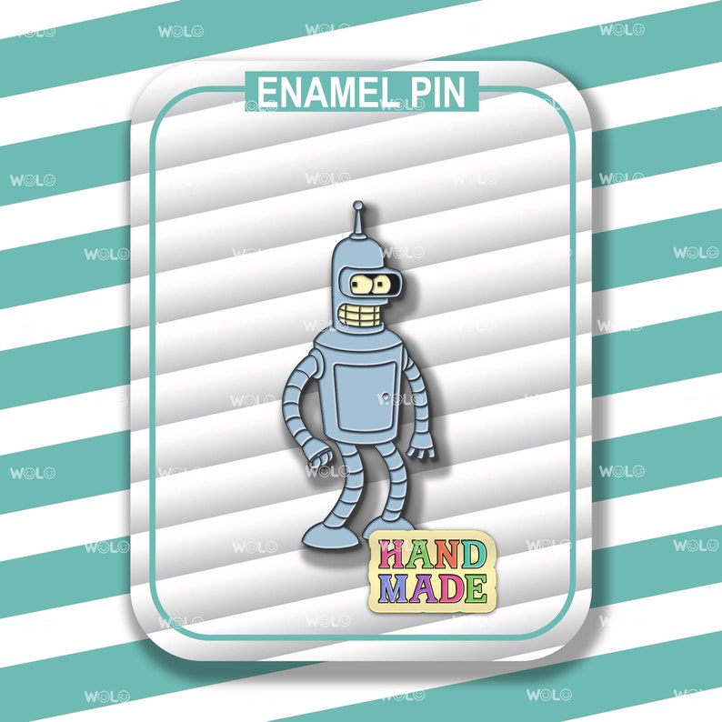 May include: A light blue enamel pin featuring a cartoon robot character with a silver antenna, yellow eyes, and a wide grin. The pin has the text "ENAMEL PIN" at the top and "HAND MADE" at the bottom, set against a striped background.