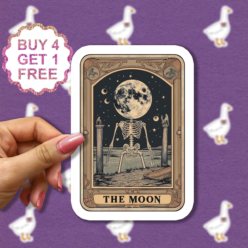 May include: A tarot card with a gold frame and a black and white illustration of a skeleton with a full moon for a head. The card reads "THE MOON" at the bottom.