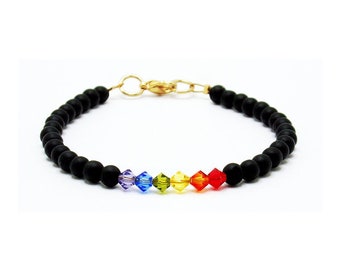 May include: A black beaded bracelet with a gold clasp and a rainbow of crystal beads.