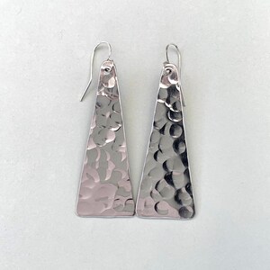 Hammered triangle earrings on plain light grey background