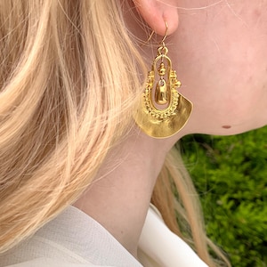 May include: Gold tone dangle earrings with a fan-shaped design and a teardrop-shaped pendant.