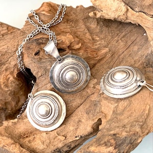 Boho convex dome coin earrings resting on natural driftwood.