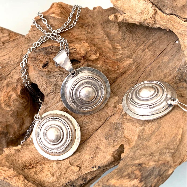 Boho convex dome coin earrings resting on natural driftwood.