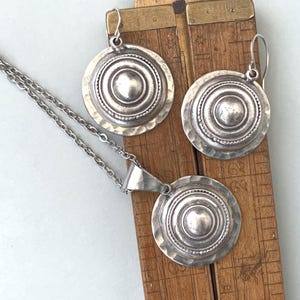 Aged silver dome earrings placed beside a ruler for scale.
