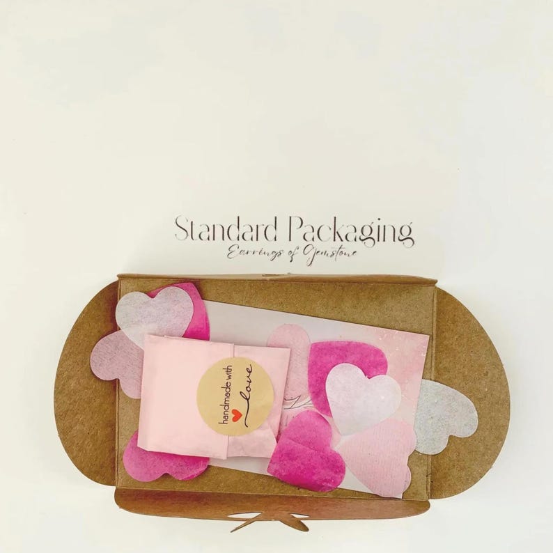 Natural card envelope with pink tissue, pink shop card and paper confetti on a pale neutral background