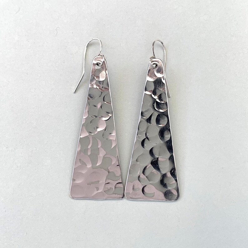 Hammered triangle earrings on plain light grey background
