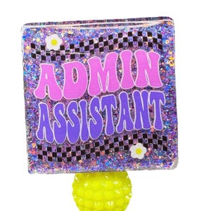 May include: A glittery square with the words "ADMIN ASSISTANT" in pink and purple. The background is a mix of purple glitter and a black and white checkered pattern. A yellow, textured base supports the square.