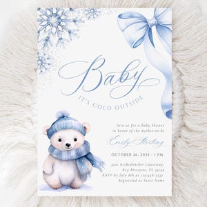 May include: Baby shower invitation with a winter theme. The invitation features a watercolor illustration of a polar bear wearing a blue hat and scarf. The text reads "Baby, It's Cold Outside". Includes event details.