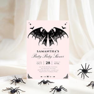 May include: A pink baby shower invitation with a bat-wing and bow design. The invitation reads "SAMANTHA'S Batty Baby Shower" with event details. Black plastic spiders are scattered around the invitation, creating a Halloween theme.