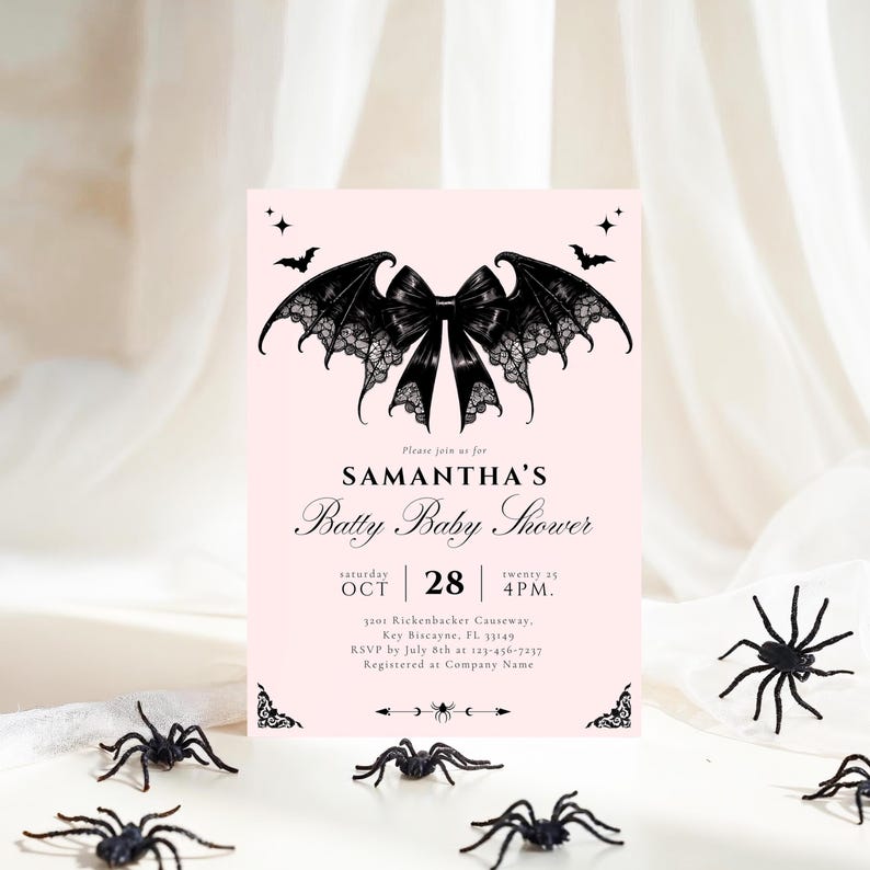 May include: A pink baby shower invitation with a bat-wing and bow design. The invitation reads "SAMANTHA'S Batty Baby Shower" with event details. Black plastic spiders are scattered around the invitation, creating a Halloween theme.
