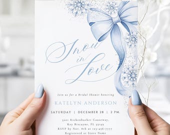 May include: A white invitation card with the text "Snow in Love" in elegant script, featuring a light blue bow and snowflake accents. The card is for a bridal shower, with details including the date, time, and honoree's name.