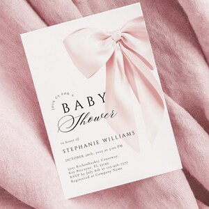 May include: A white baby shower invitation with a pink satin bow. The invitation reads "Join us for a Baby Shower in honor of Stephanie Williams, October 28th, 2015 at 3:00 PM, 1100 Rickenbacker Causeway, Key Biscayne, FL 33149, RSVP by July 8th at 123-456-7777, Registered at Company Name."