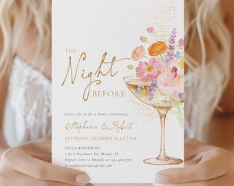May include: A white invitation card featuring gold text that reads The Night Before, Stephanie & Robert, and event details. A watercolor illustration of a champagne coupe glass filled with pink, orange, and purple flowers sits on the right side.