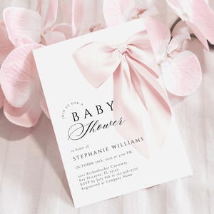 May include: A white baby shower invitation with a pink bow on top. The invitation reads "Join us for a Baby Shower" in a script font. The text below reads "In honor of Stephanie Williams, October 18th, 2015 at 3:00 PM, 1200 Rickenbacker Causeway, Key Biscayne, FL 33149, RSVP by July 8th at 123-456-7777, Registered at Company Name."