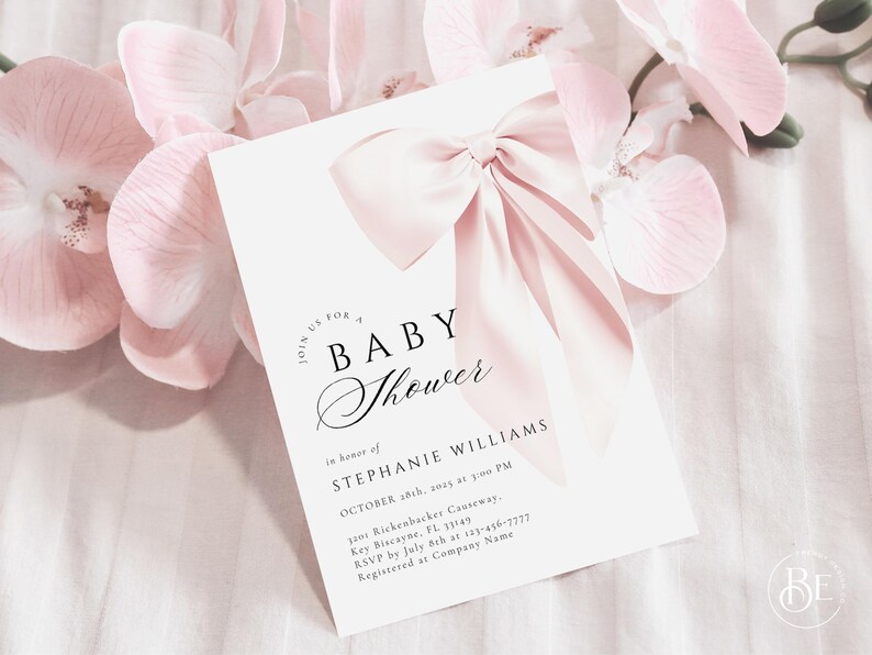 May include: A white baby shower invitation with a pink bow on top. The invitation reads "Join us for a Baby Shower" in a script font. The text below reads "In honor of Stephanie Williams, October 18th, 2015 at 3:00 PM, 1200 Rickenbacker Causeway, Key Biscayne, FL 33149, RSVP by July 8th at 123-456-7777, Registered at Company Name."