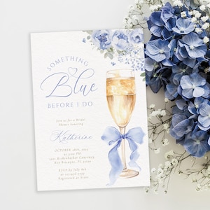 Op de afbeelding: Een uitnodiging voor een bruidsdouche met de tekst "Something Blue Before I Do" in elegant schrift. De uitnodiging bevat een aquarel illustratie van een champagneglas met een blauw lint en bloemaccenten. De uitnodiging bevat de datum, tijd en locatie.