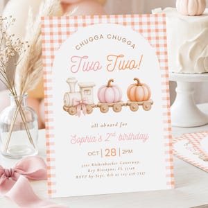May include: A rectangular birthday invitation card with an orange gingham border. The center features an arched design with a train carrying two pumpkins, text reading Chugga Chugga Two Two!, Sophia's 2nd birthday, Oct 28, 2pm, and address details.