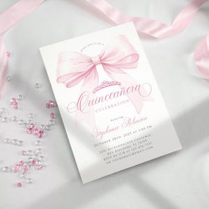 Pode incluir: Um cart&atilde;o de convite branco com uma ilustra&ccedil;&atilde;o de um grande la&ccedil;o rosa. O cart&atilde;o anuncia uma "Celebra&ccedil;&atilde;o de Quincea&ntilde;era" e inclui detalhes do evento, como o nome da homenageada, a data, a hora e o local. Fita rosa e pedras preciosas decorativas no fundo.