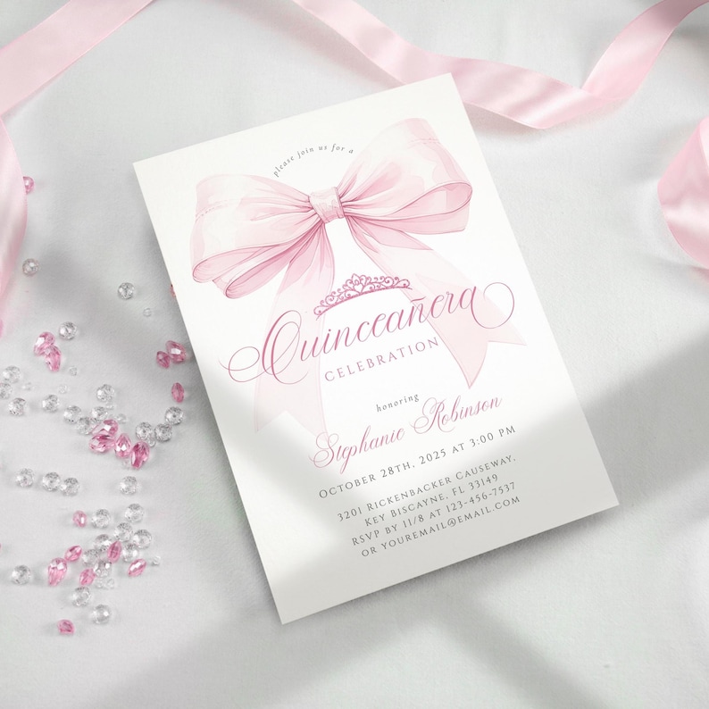 Pode incluir: Um cart&atilde;o de convite branco com uma ilustra&ccedil;&atilde;o de um grande la&ccedil;o rosa. O cart&atilde;o anuncia uma "Celebra&ccedil;&atilde;o de Quincea&ntilde;era" e inclui detalhes do evento, como o nome da homenageada, a data, a hora e o local. Fita rosa e pedras preciosas decorativas no fundo.