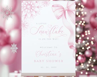 May include: A white baby shower sign with pink accents, featuring a snowflake design and a pink bow. The text reads "A Little Snowflake is on the Way!" and welcomes guests to Christine's baby shower on 02.22.2025.