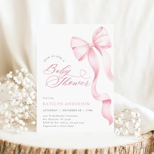 May include: A baby shower invitation with a watercolor pink bow and flowing ribbons. The invitation includes the text "Join us for a Baby Shower" and details for Katelyn Anderson's shower, including the date, time, and location.