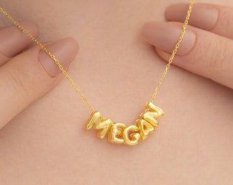 May include: A gold necklace with the name "MEGAN" spelled out in bubble letters.