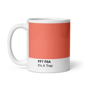 May include: White ceramic mug with a coral colored square and the text "FF7 F6A It's A Trap" printed on the front.