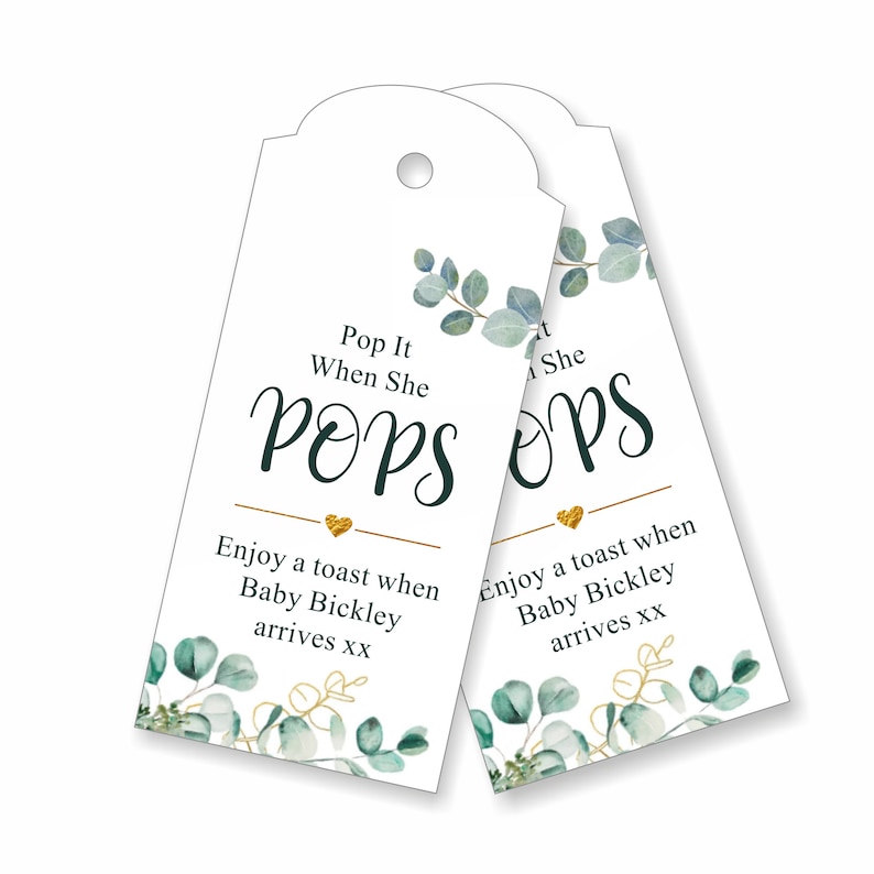 May include: Two white favor tags with gold and green eucalyptus designs. The text on the tags reads "Pop It When She Pops" and "Enjoy a toast when Baby Bickley arrives xx".