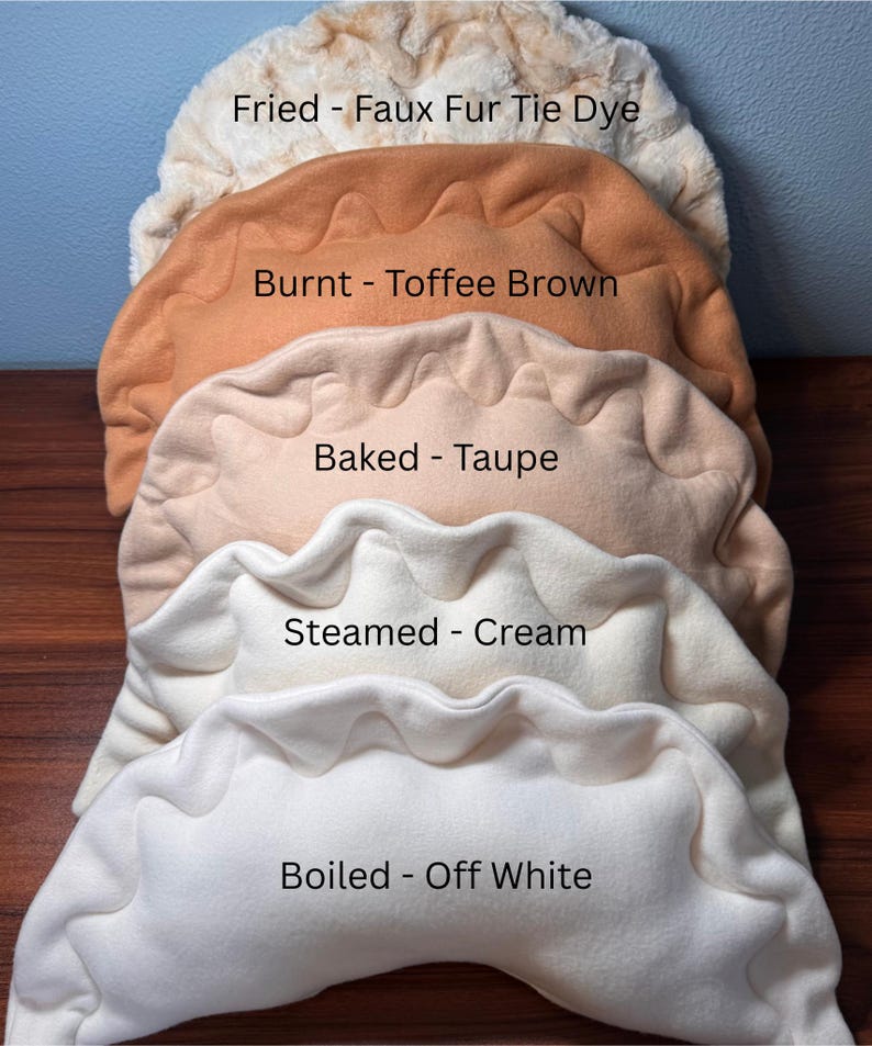 May include: A stack of plush, dumpling-shaped pillows in various colors. The pillows are labeled "Fried - Faux Fur Tie Dye", "Burnt - Toffee Brown", "Baked - Taupe", "Steamed - Cream", and "Boiled - Off White".