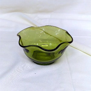 May include: A green glass bowl with a wavy rim. The bowl is empty and has a slight sheen.