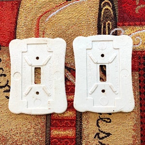 May include: Two white ceramic light switch plates with the text "Cardinal China" and "Carteret N.J." printed on them.