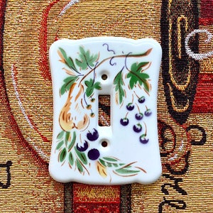 May include: White ceramic light switch cover with a hand-painted design of green leaves, yellow pears, and purple berries.