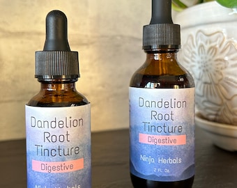 May include: Two brown glass bottles with black dropper tops and labels. The labels are white with blue watercolour designs and black text. The text on the labels reads "Dandelion Root Tincture Digestive Ninja Herbals" and the size of the bottles in fluid ounces.