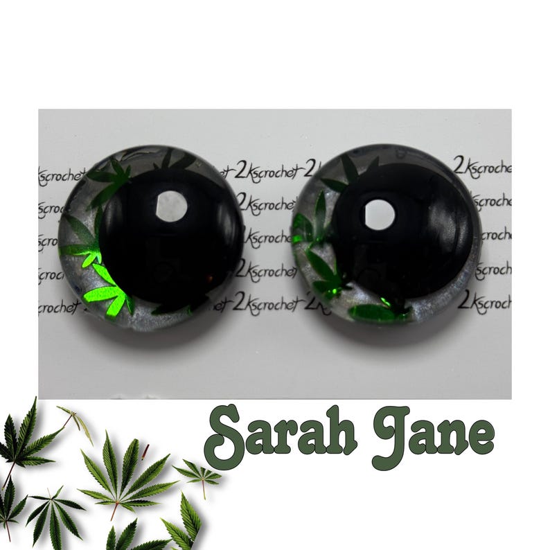 Peut inclure: Deux boucles d'oreilles rondes, noires et transparentes, avec un motif de feuille de cannabis. Les boucles d'oreilles ont un centre noir avec un point blanc et des feuilles de cannabis vertes sur les bords. Le texte "Sarah Jane" est en dessous.