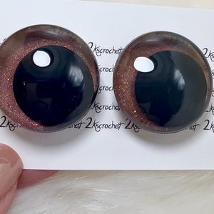 May include: Two round, black and brown glass eyes with a white pupil. The eyes have a glittery, shimmery finish.